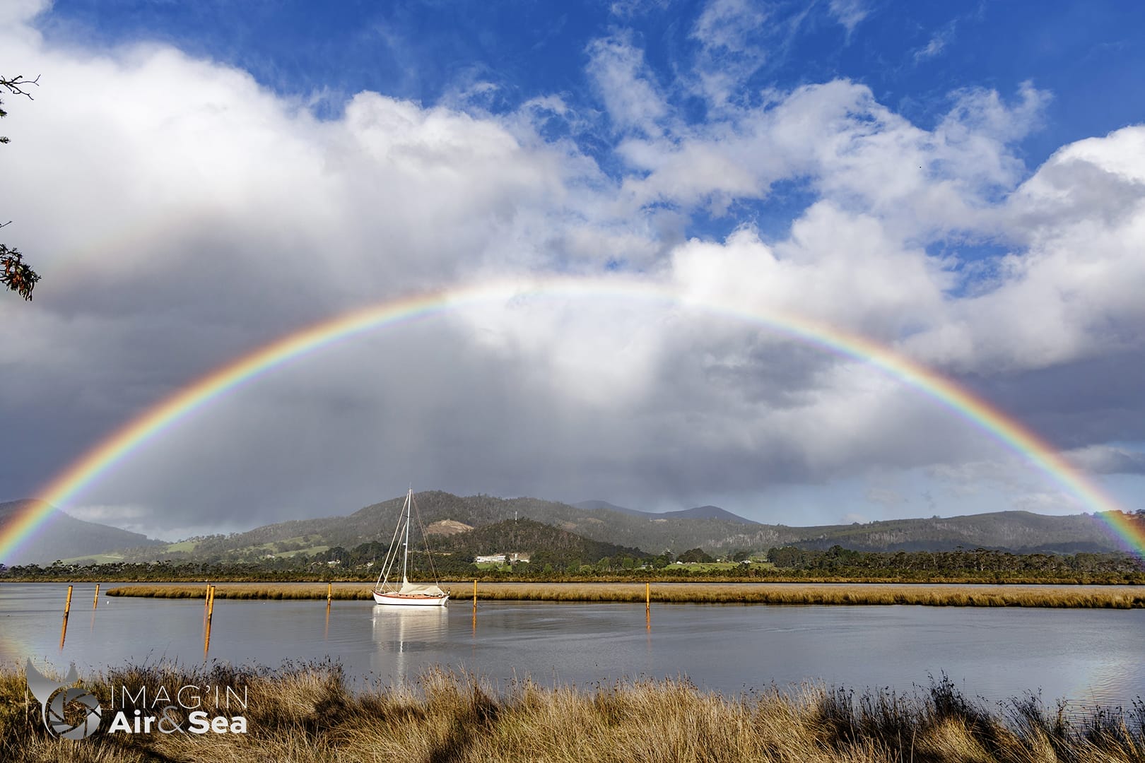 Photo d'una magnifique arc en ciel au dessus d'un voilier au mouillage en Tasmanie