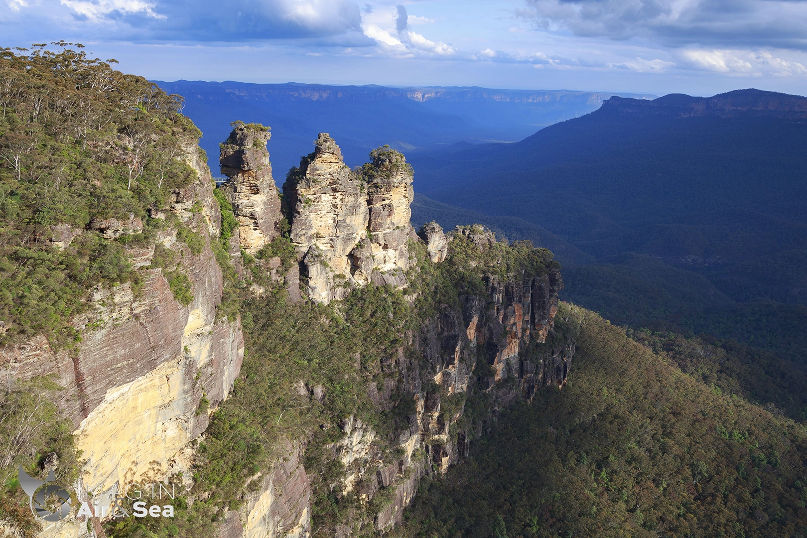 Photo des 3 sisters éclairée par le soleil couchant avec les Blue mountains en arrière plan.